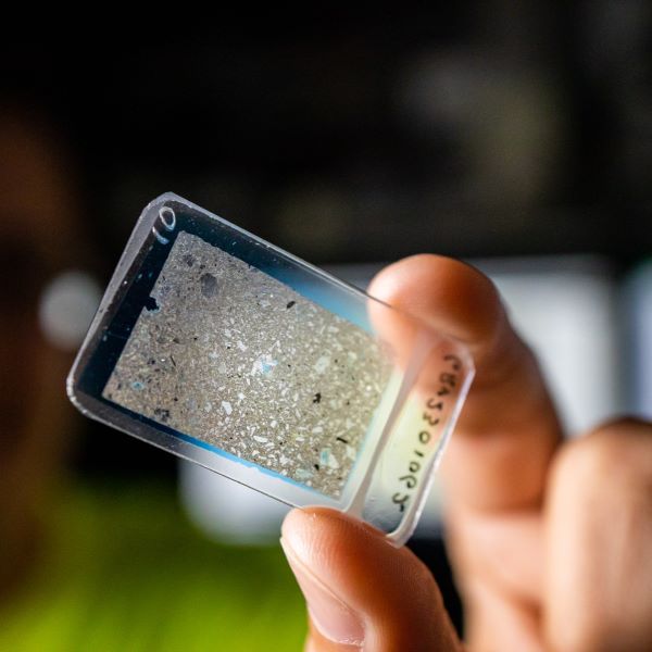 Student holds a microscope slide associated with a geological study in Guatemala