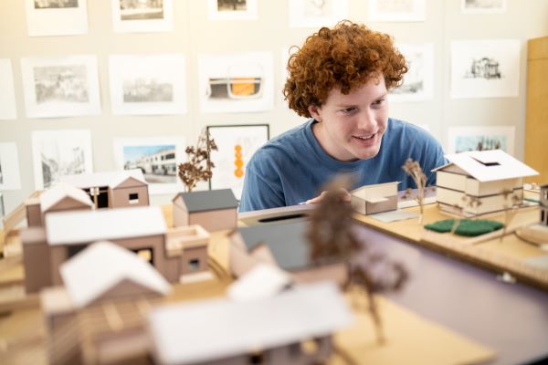 A student inspects a paper model home in the design studio
