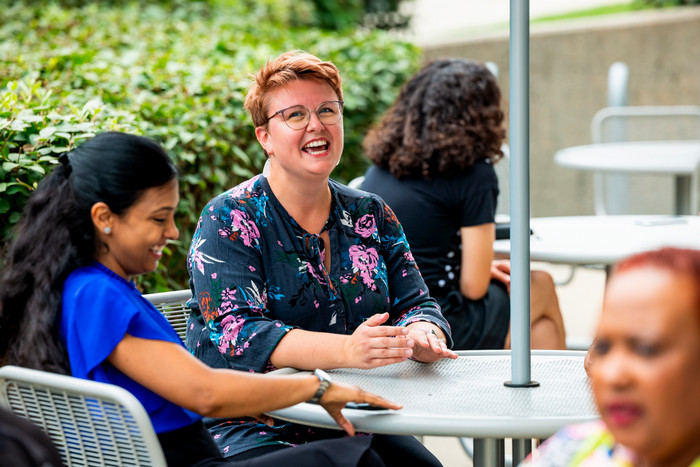 staff member laughs while sitting at a table with other staff