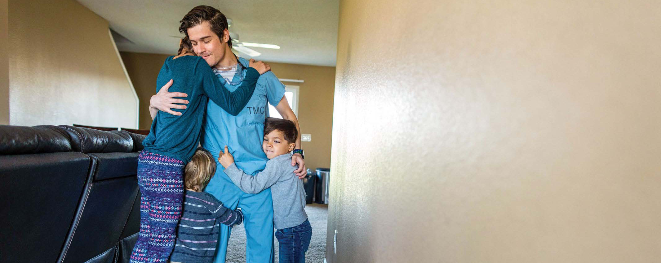 Father in medical scrubs hugs his children