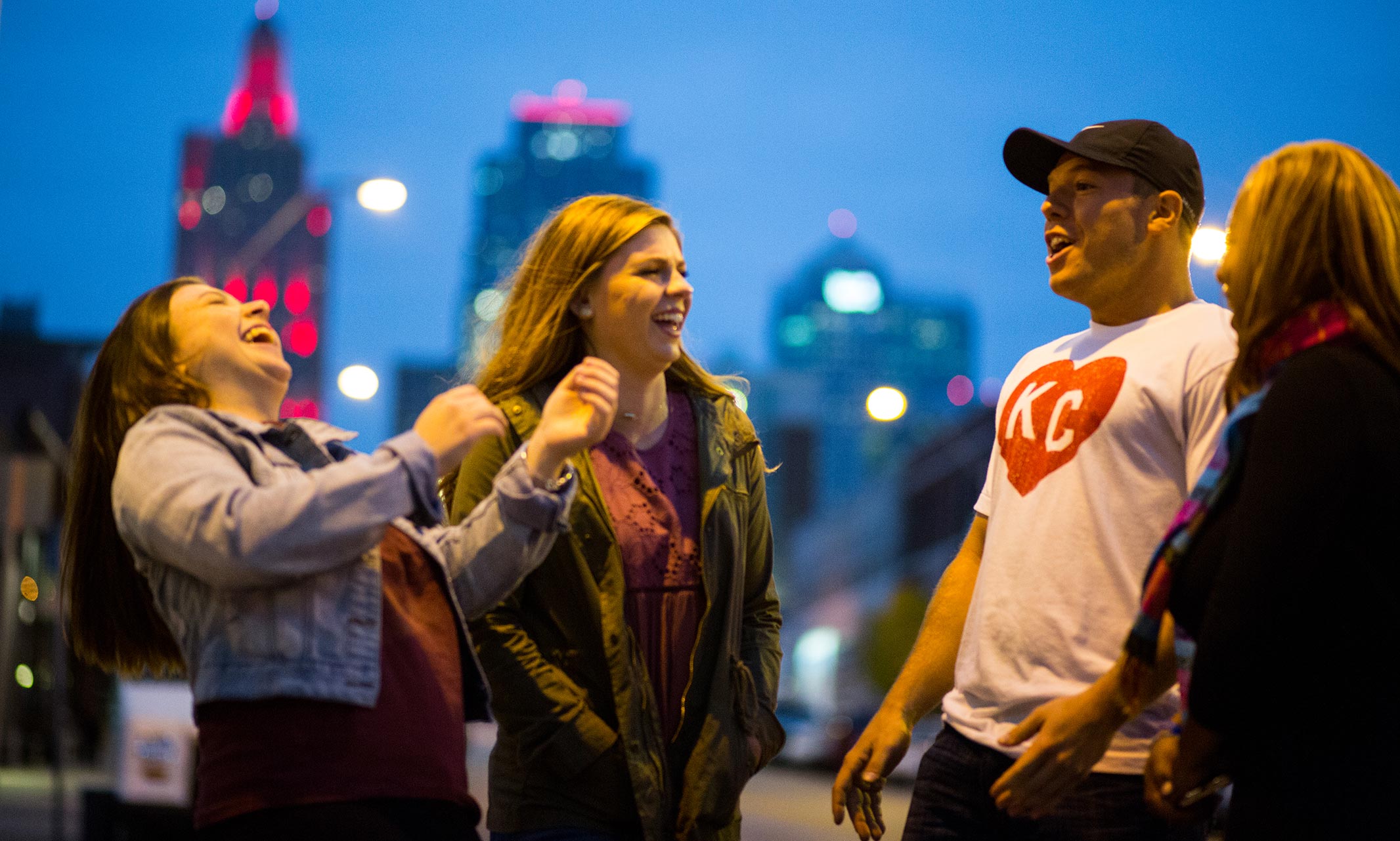 Four people having a joyful conversation with Kansas City skyline in the background