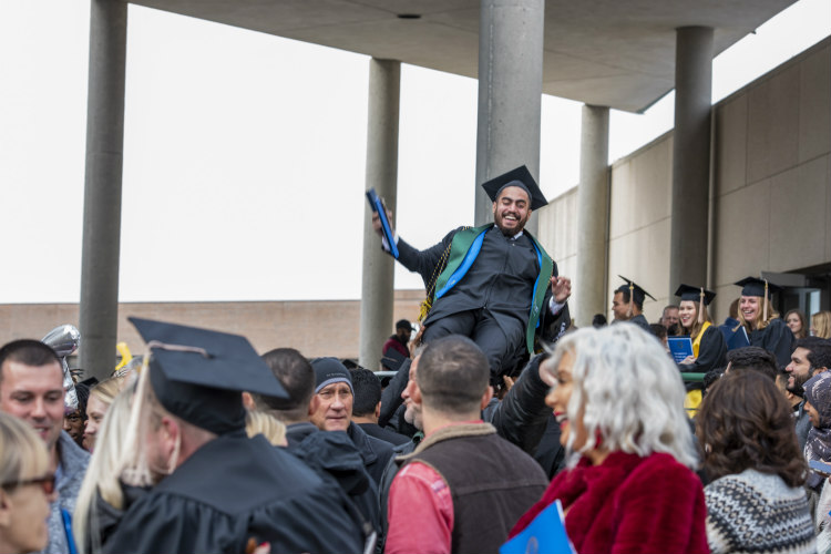 Student crowd surfing outside Swinney Center after graduation.