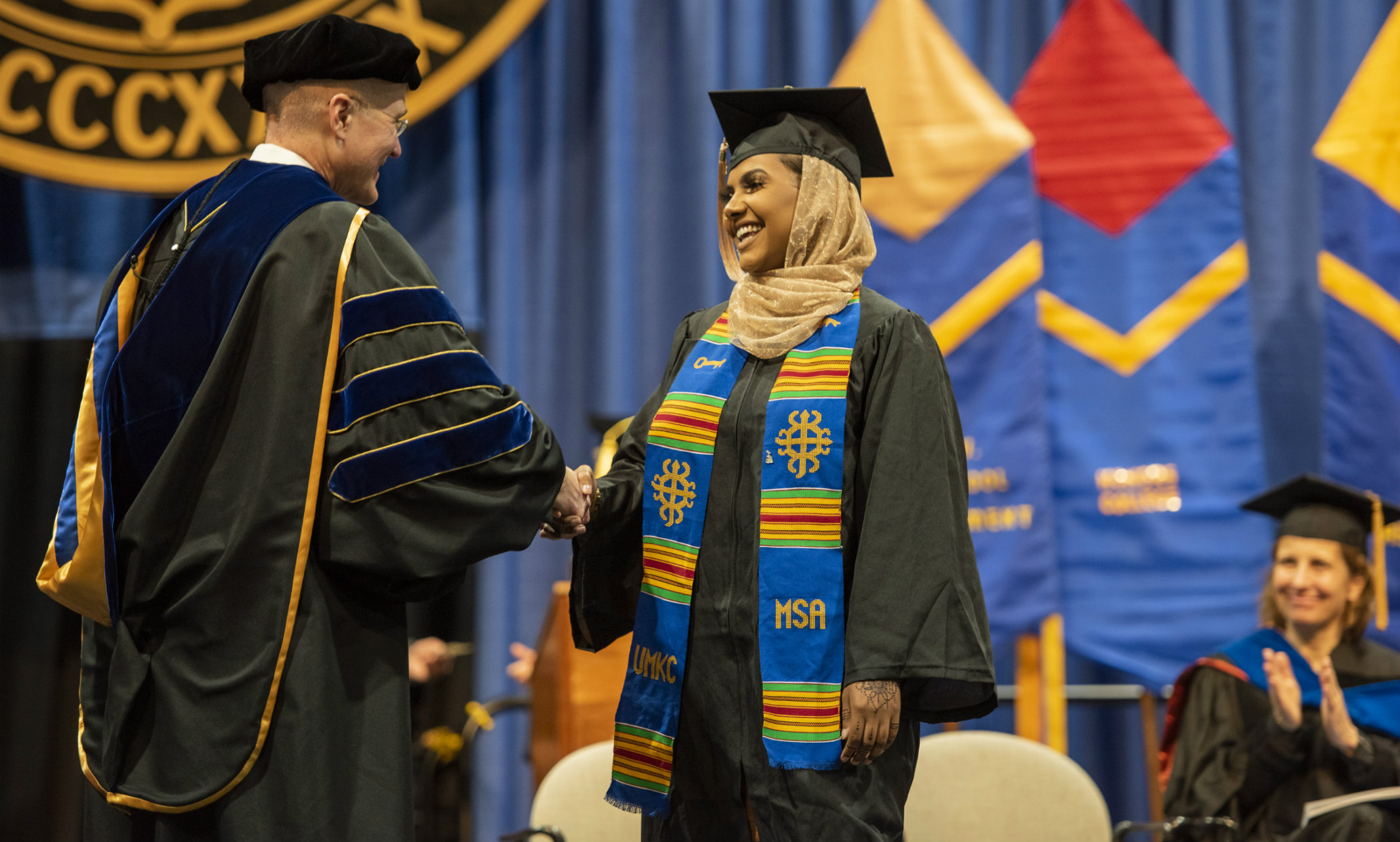 Female student receives her degree onstage during mid-year commencement.