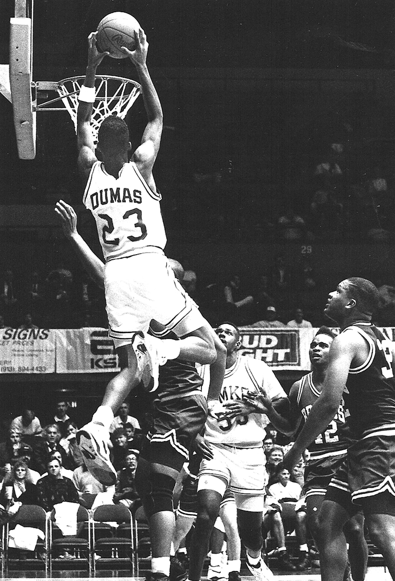 Dumas dunks over his opponent in a black and white photo