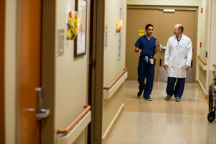 Student Akash Jani and Mike Vlastos, M.D. walk in a hallway.