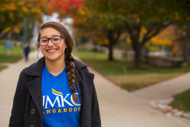 UMKC student Daphne Posadas stands outside on the Volker Campus, trees in the background