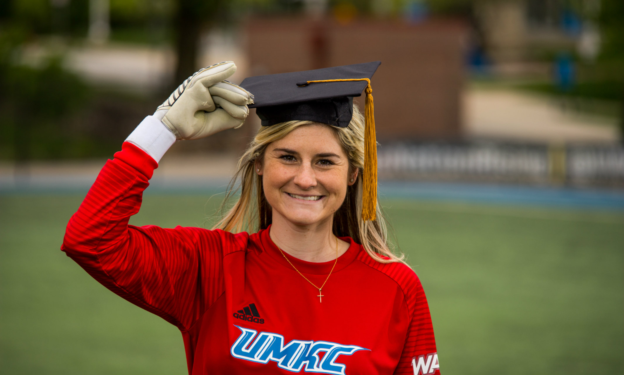 UMKC Soccer goalkeeper Anna Lillig stands wearing a mortar board
