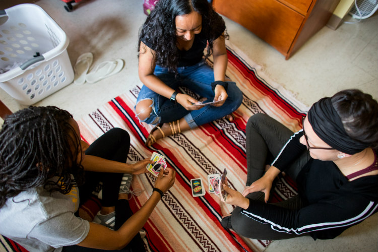 Three women playing cards in a dorm. Birds' eye view from above.