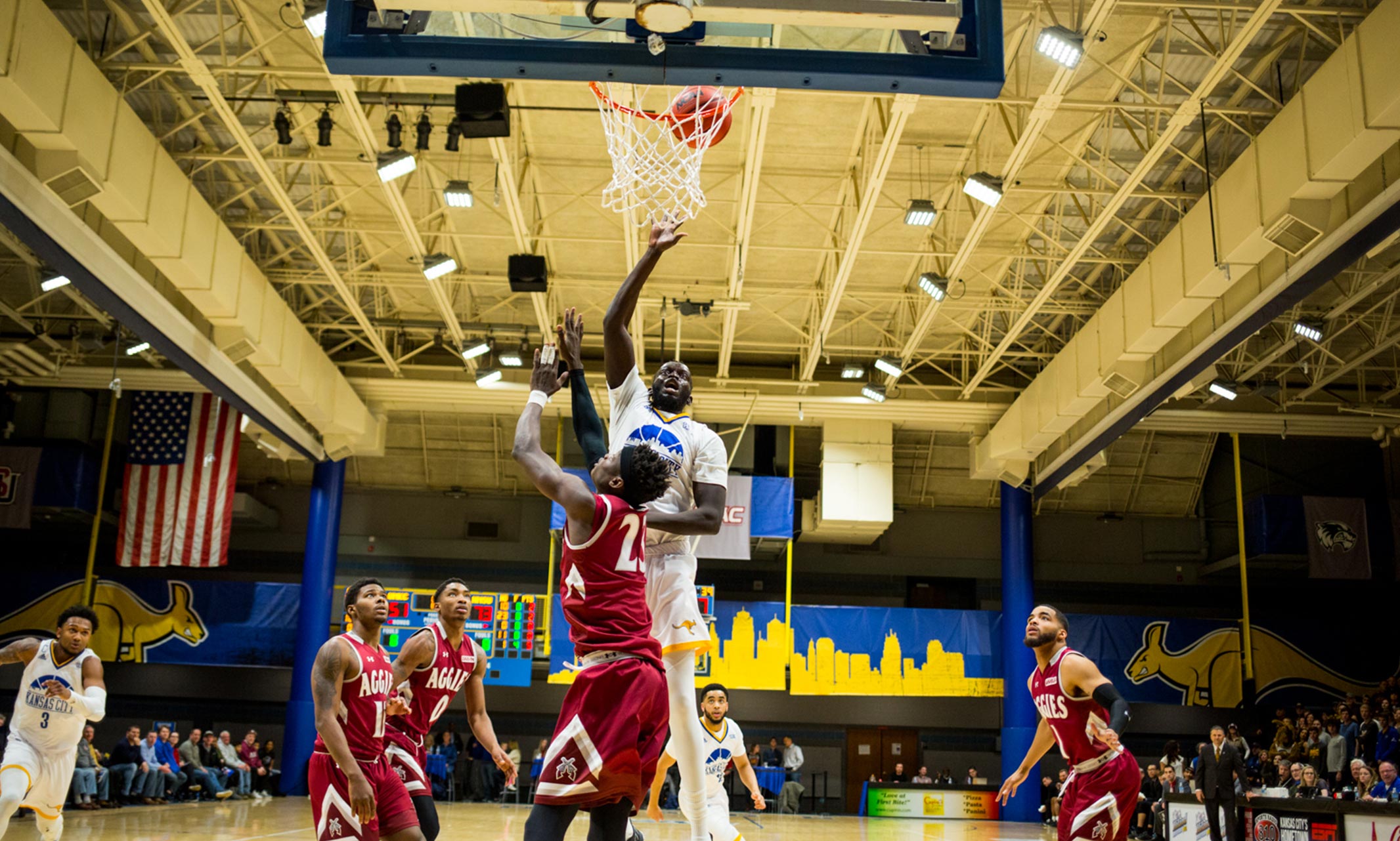 UMKC men's basketball player lays the ball up over several opponents