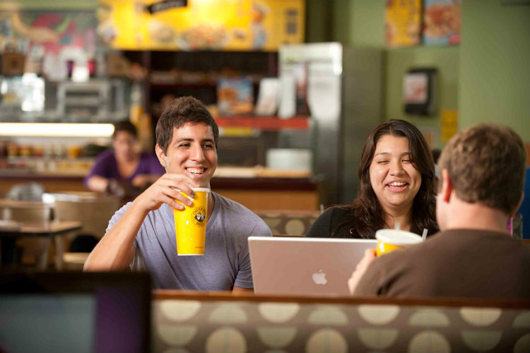 A male and female student sitting down in a booth