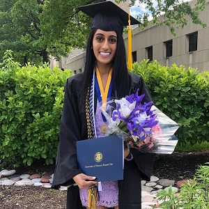 New graduate Ravali Reddy with her degree and flowers.