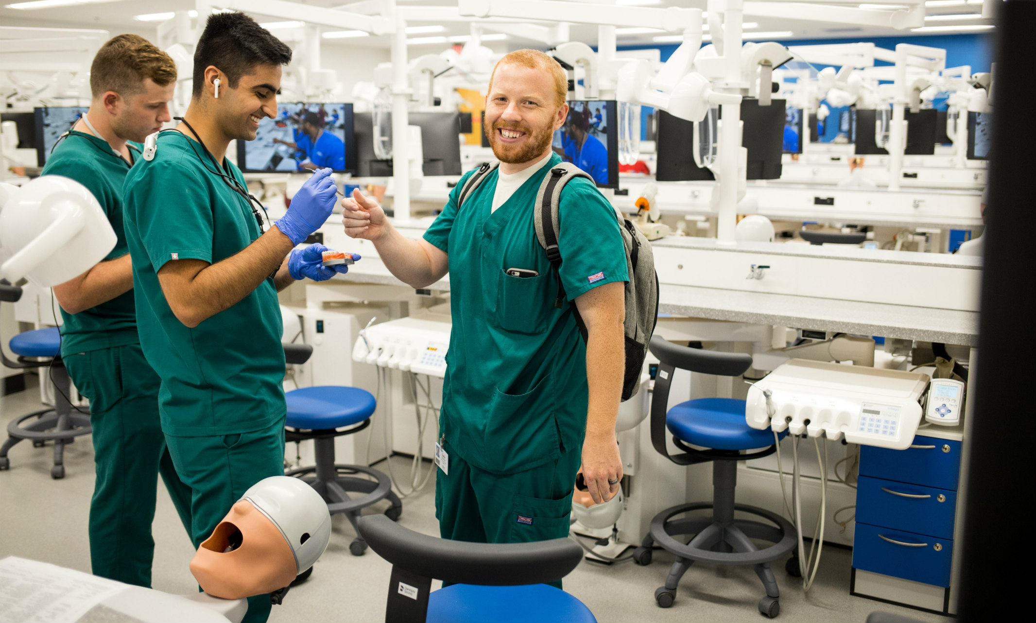 Three UMKC dental students who present as males stand among operators in the new dental simulation lab.