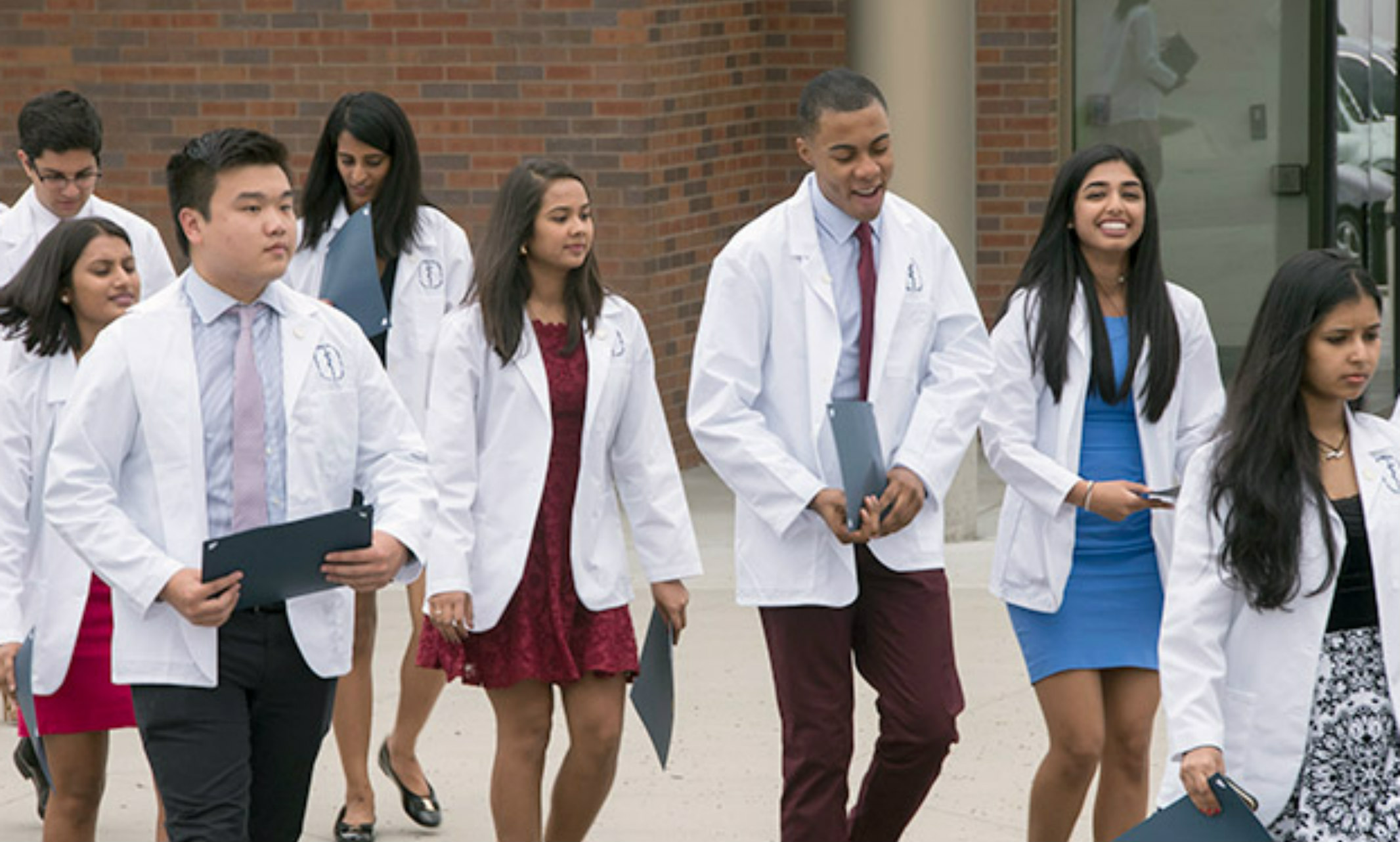 UMKC School of Medicine students presenting in diverse ethnicities walk in their white coats