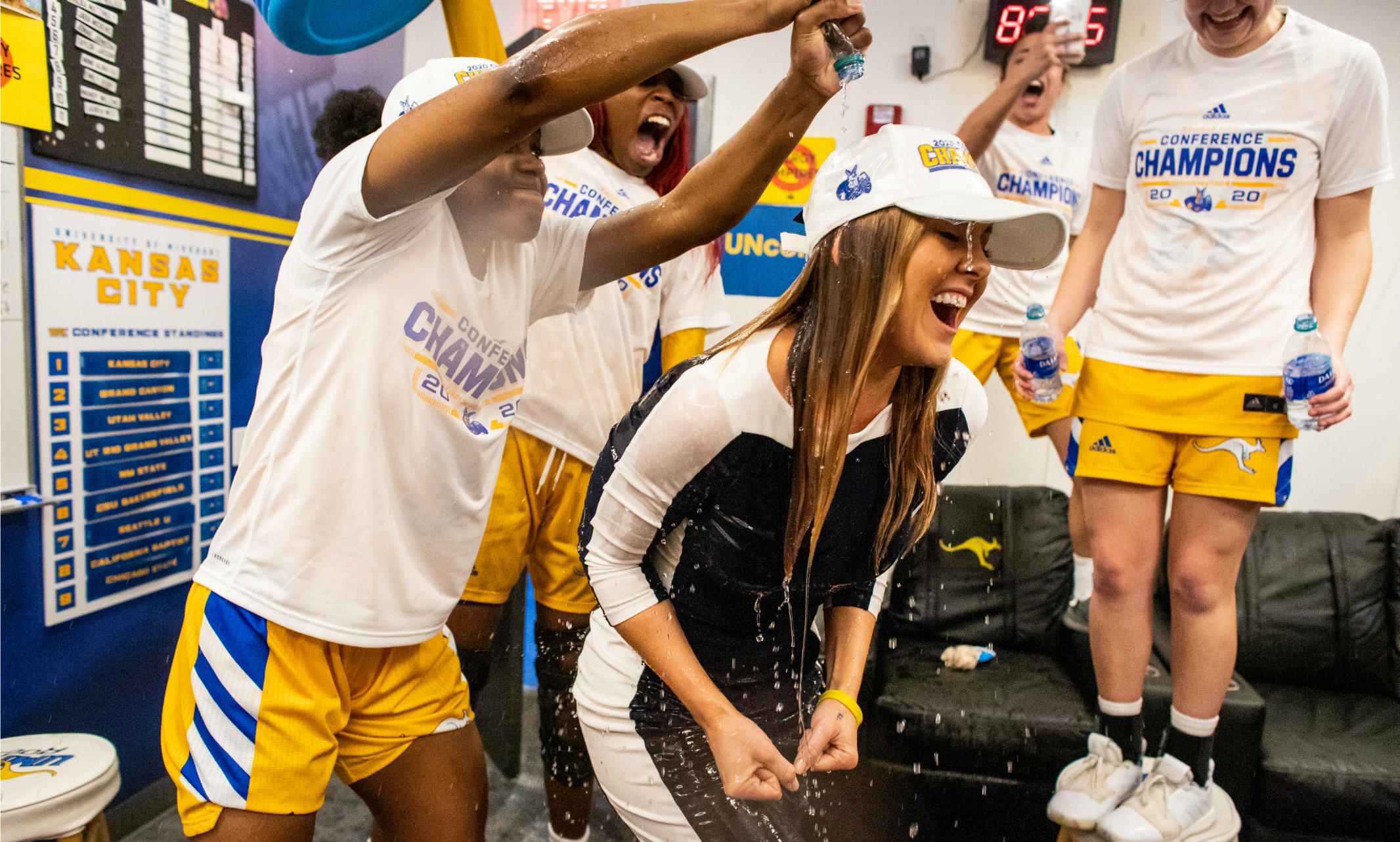 Girls pour bottles of water over Coach Jacie – conference champion gear front and center in photo