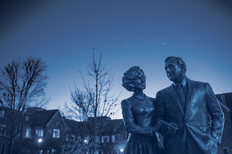 statue of Henry and Marion Bloch outside Bloch Heritage Hall at sunset