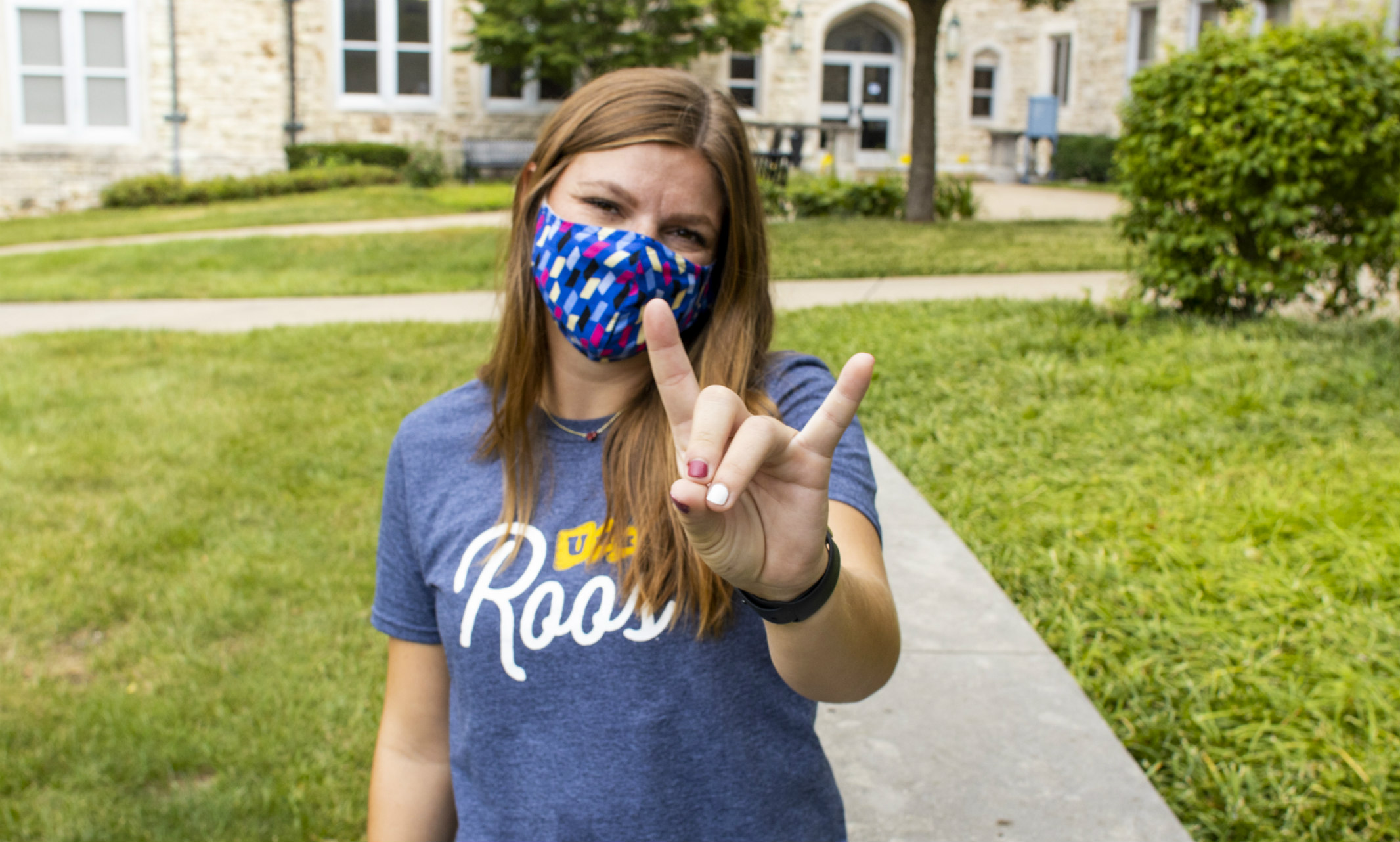 Female student wearing fce mask and flashing Roo hand sign