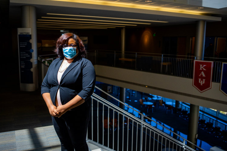 Keichanda poses with mask standing at the Student Union stairwell with student organization banners in the background