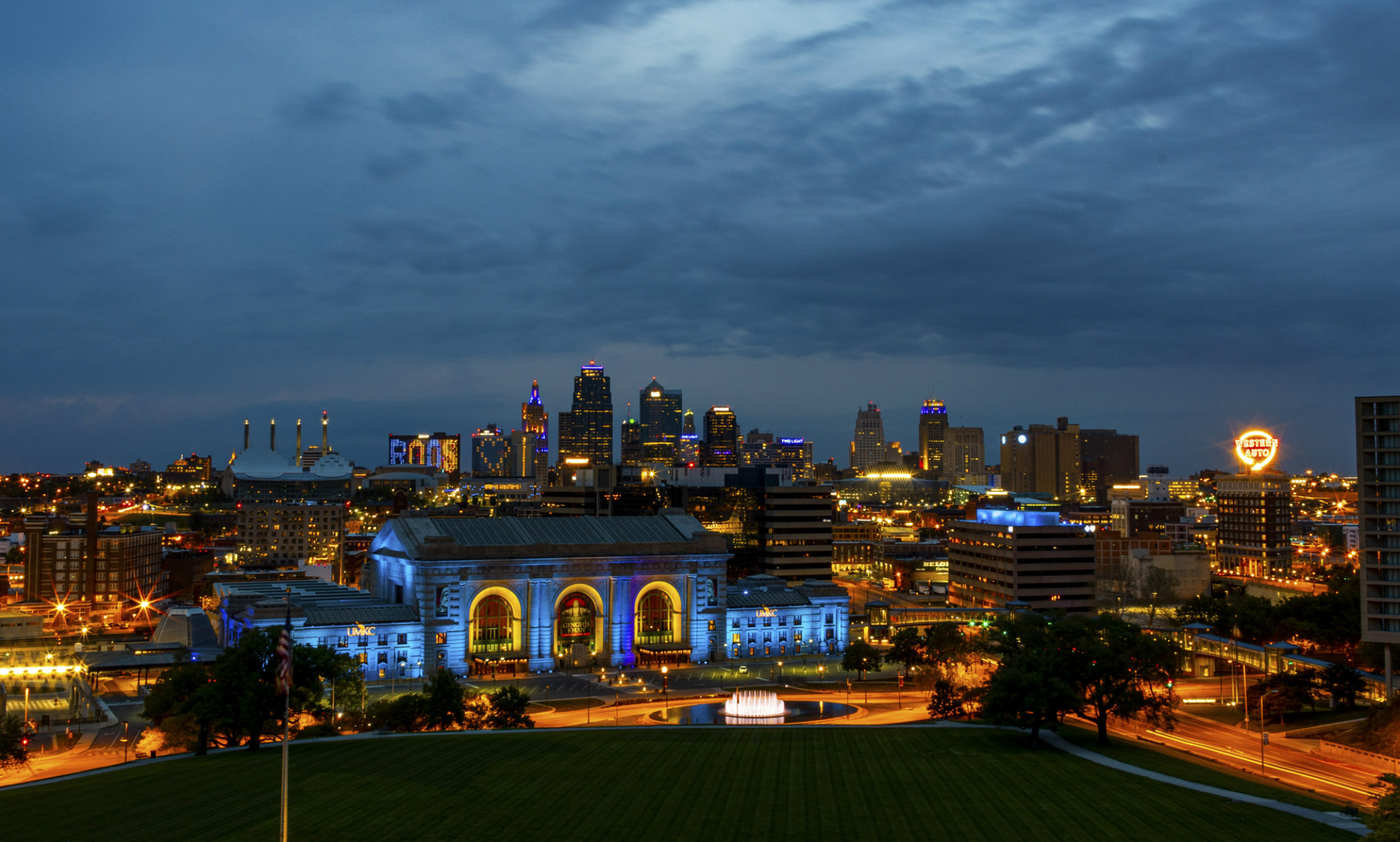 The Kansas City skyline is illuminated blue and gold. Union Station is in forefront.
