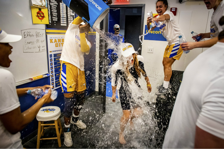Locker room celebration of water being poured over Women's Basketball Coach Jacie Hoyt