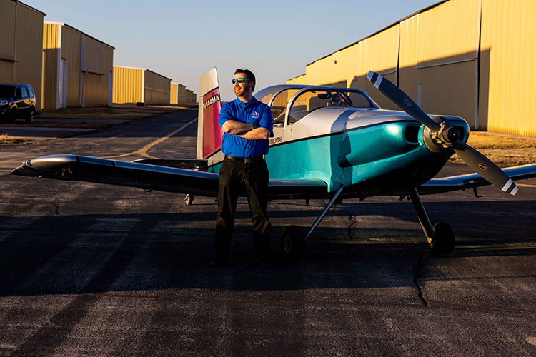 Faculty member stands on runway with his plane