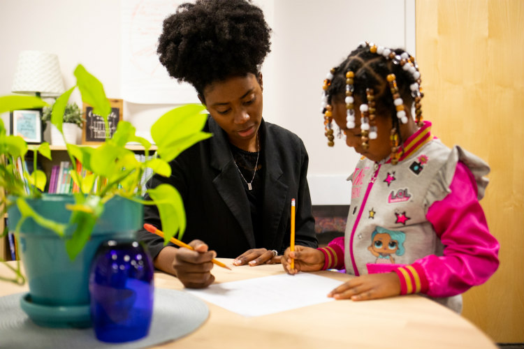 black female teacher and black female student work together on classroom assignment