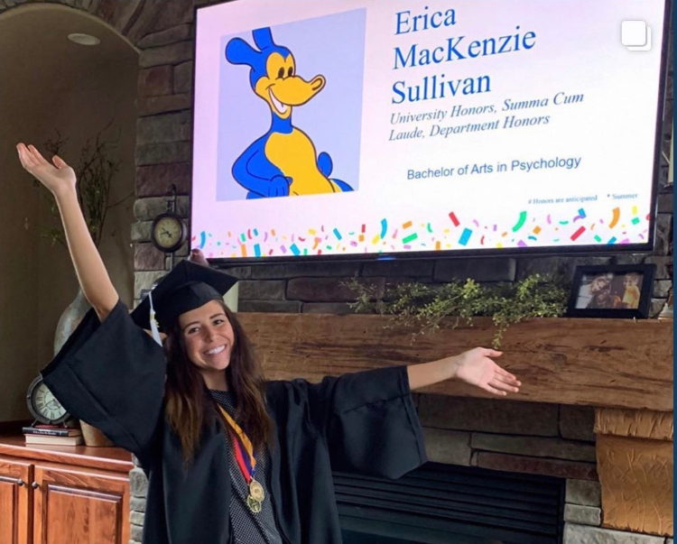 graduate in cap and gown throws her hands up in the air when her name appears on the streamed commencement ceremony feed