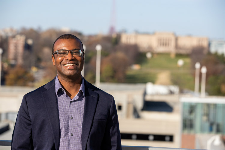 Antonio standing on Student Union rooftop with campus and Kansas City skyline in the background