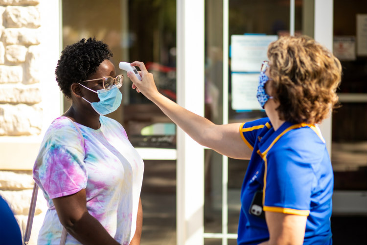 A UMKC staff member takes a student's temperature at move-in