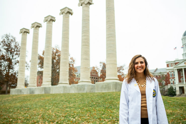 A female UMKC School of Pharmacy student in front of the columns at the University of Missouri in Columbia.