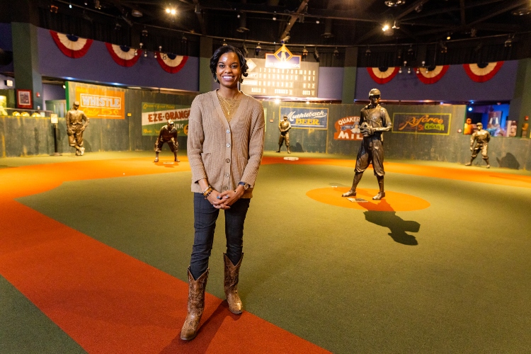 Kiona Sinks stands on the baseball diamond at the Negro Leagues Baseball Museum