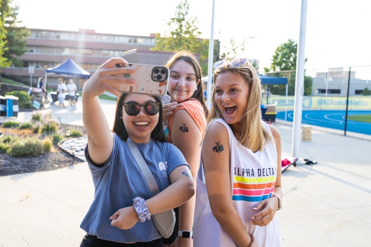 three students with Roo stickers on their arms take a selfie