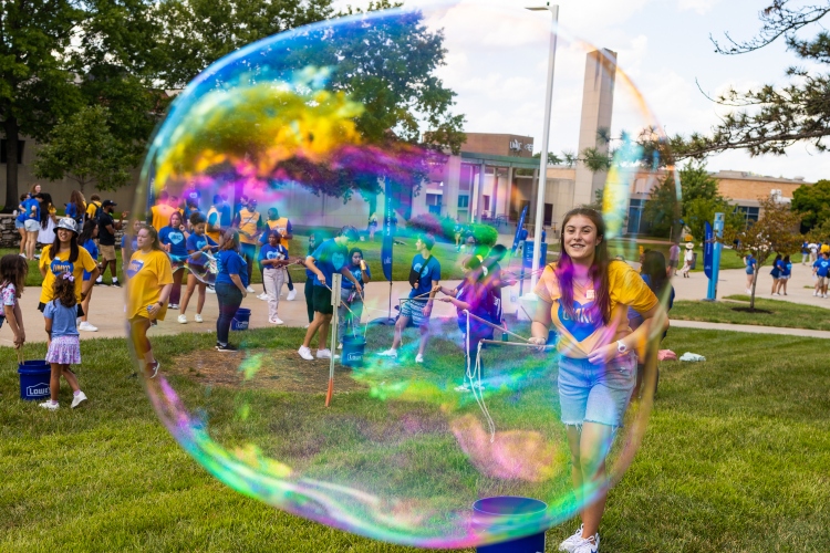 A student smiles with a large bubble in front of her