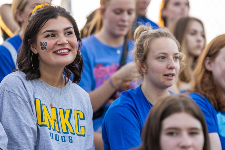 A student watches the soccer match smiling with a roo sticker on her cheek
