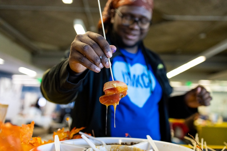 A student in a UMKC heart t-shirt holds an object that has just been dipped in liquid