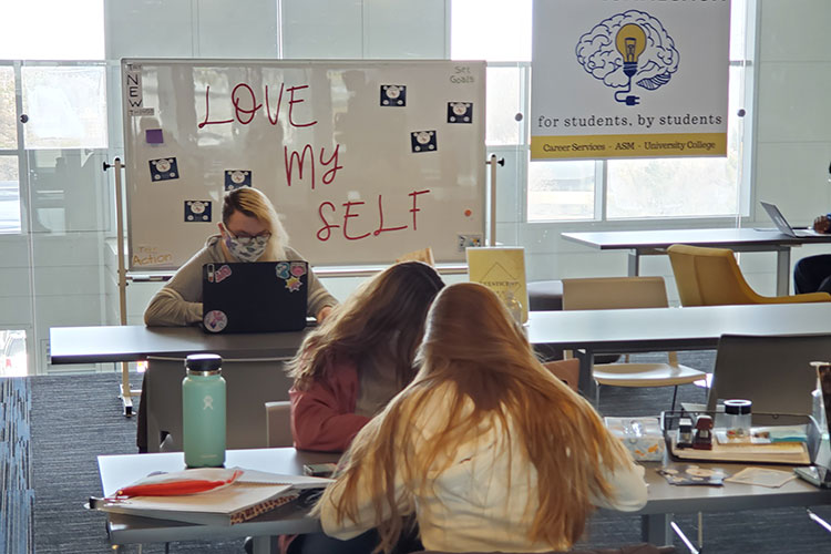 Students studying in front of board that says "Love Your Self"