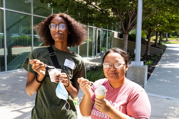 Aaliyah Daniels, on the right, and her friend smile for the camera while eating ice cream outside