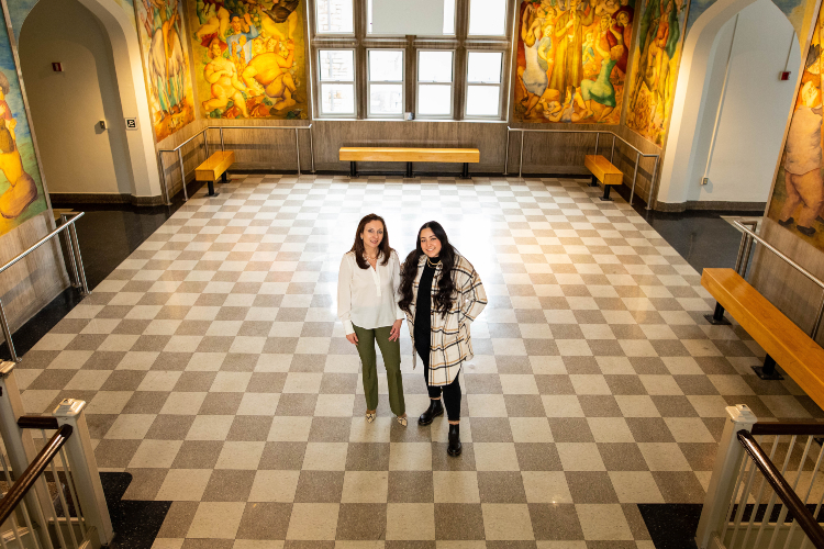 Victoria and Viviana in the checkered floor lobby surrounded by the murals