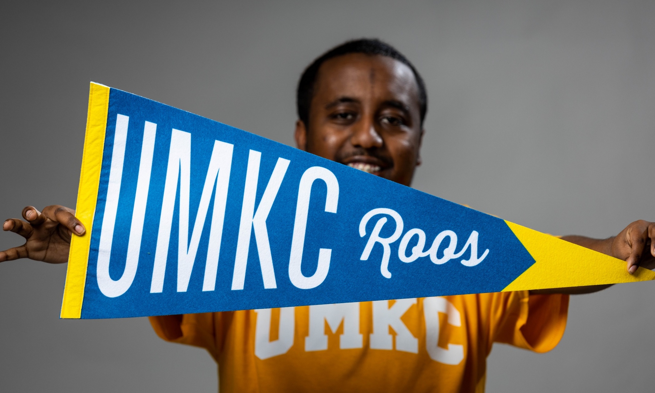 Transfer student Nabil Abas holds a UMKC pennant in the forefront of the frame
