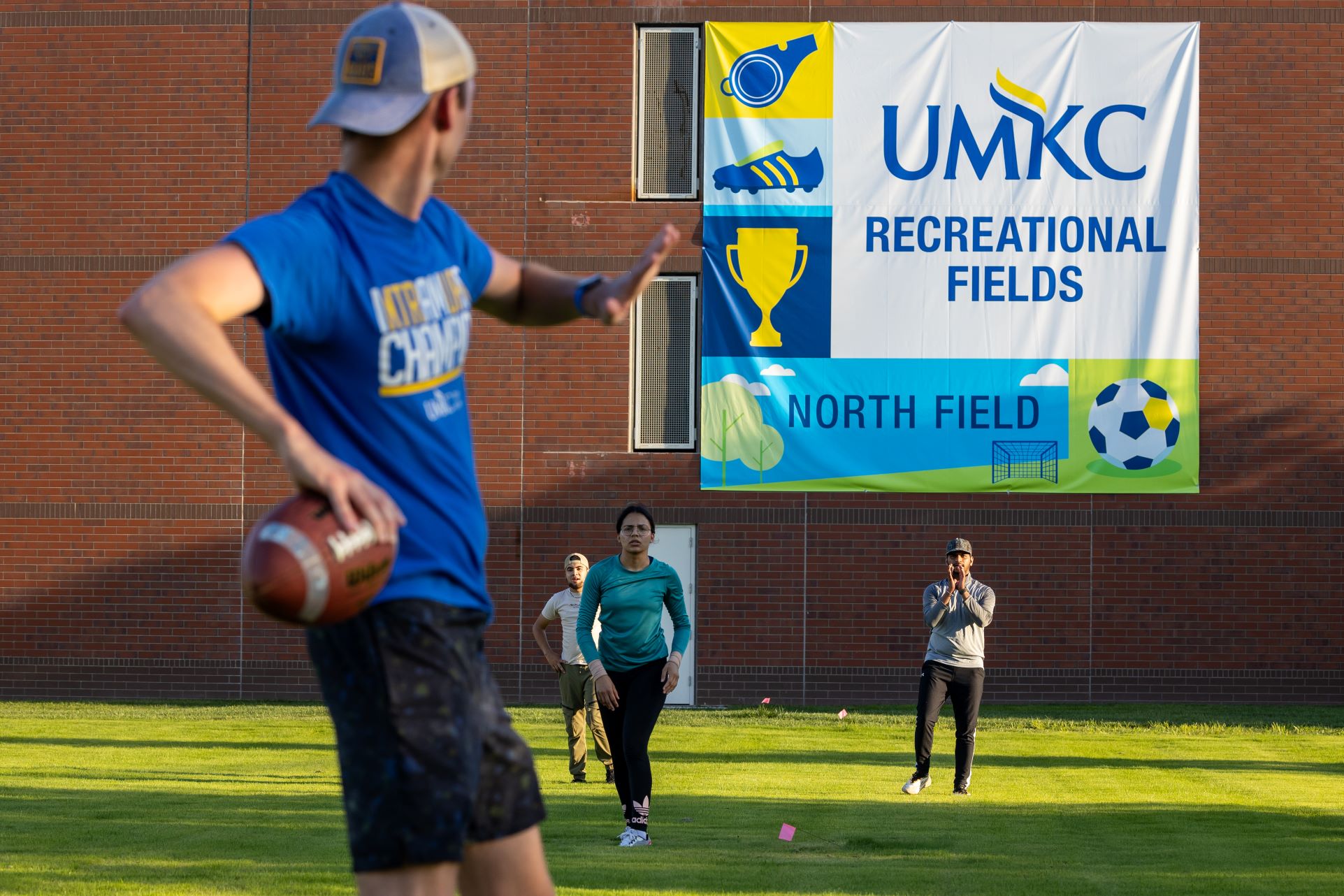 Image of a student about to throw a football with three other players waiting to catch it.