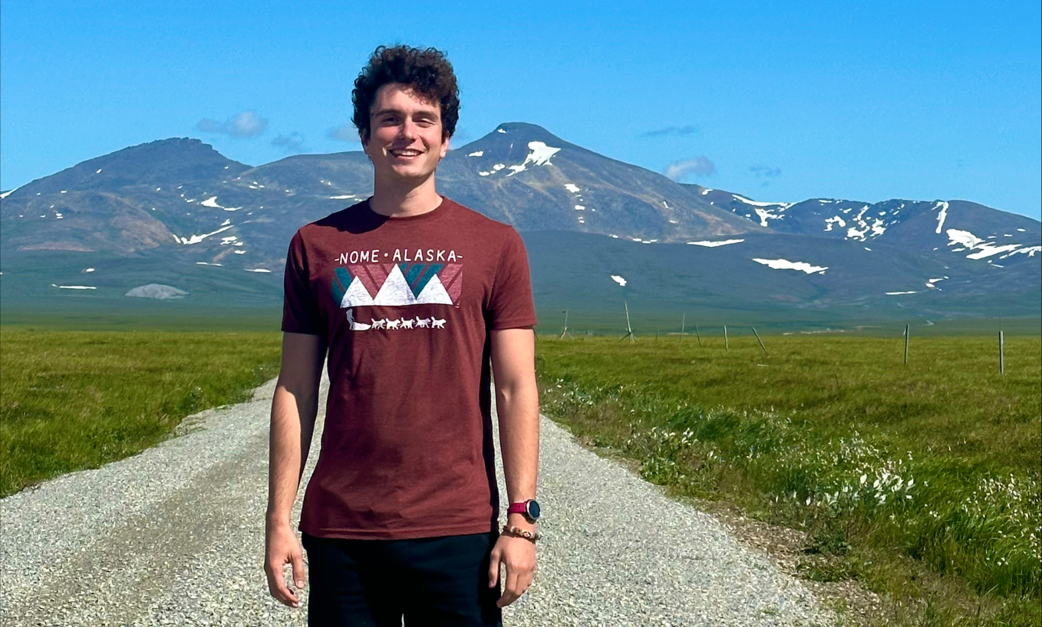 Photo of Caleb Feuerbacher in Alaska standing outdoors with large mountain in background