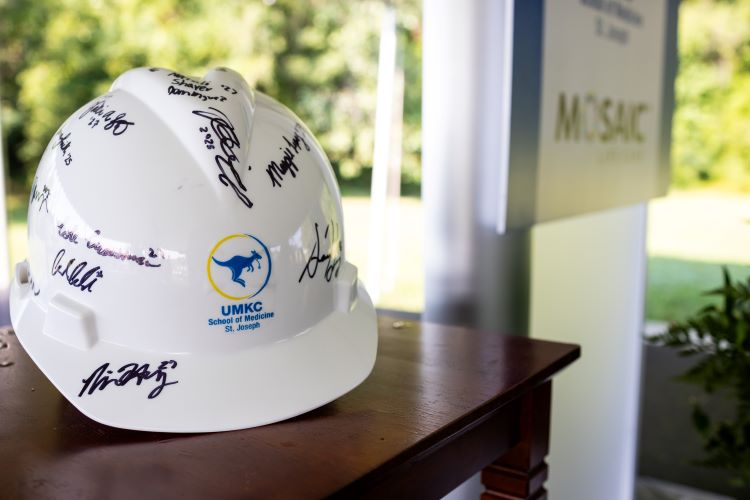 A UMKC School of Medicine hardhat covered in signatures sits on a table