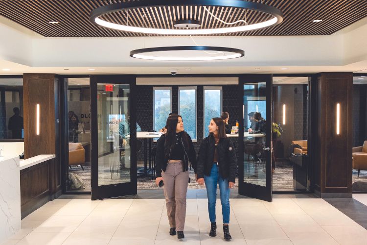 Two students walk in the front door of Bloch Heritage Hall, into a bright, airy atrium