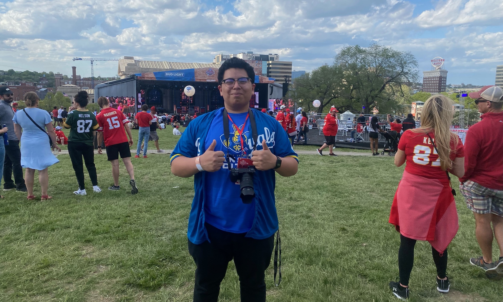 Cristian Martinez stands on the lawn at an NFL Draft event. Union Station and the large stage are visible behind him and there are people all around.