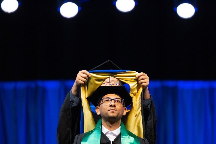 Graduating student gets hooded on stage
