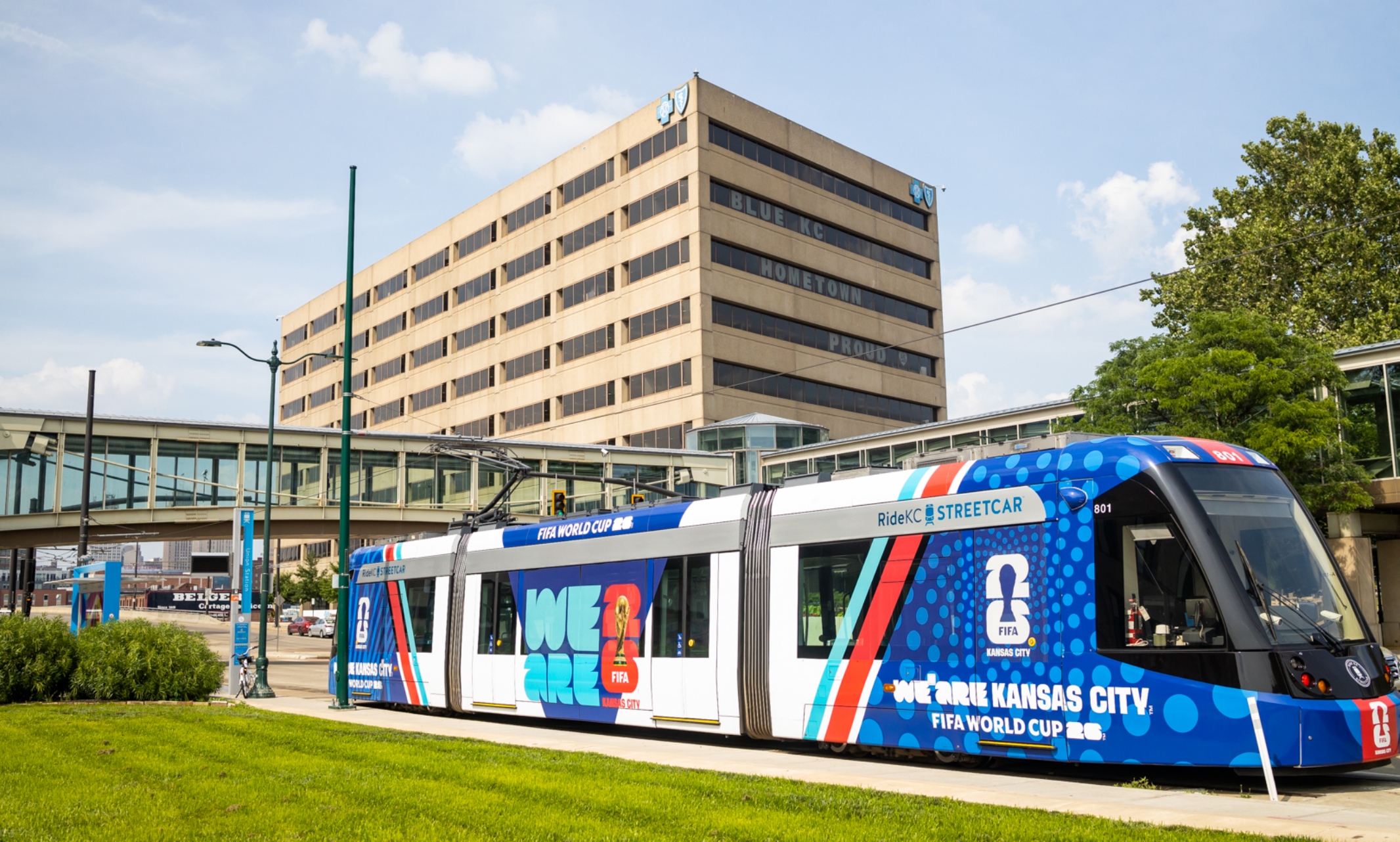The Kansas City streetcar sits in front of the Blue Cross and Blue Shield building with the Link stretching above the streetcar