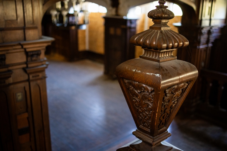 A close up of an ornate staircase newel carved in a tudor style