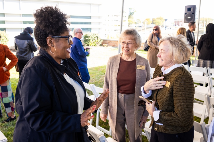 Janette Berkley-Patton speaks with members of the community outdoors under an event tent 