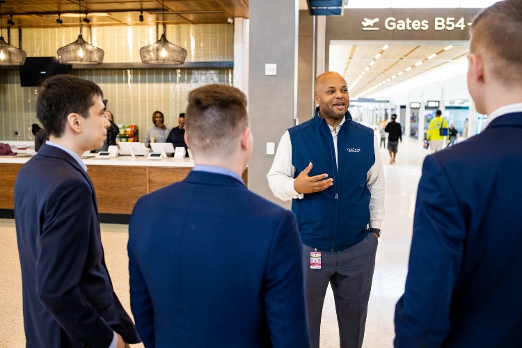 Three students have a conversation with Vantage Airport Group General Manager Lovell Holloway inside the KCI terminal