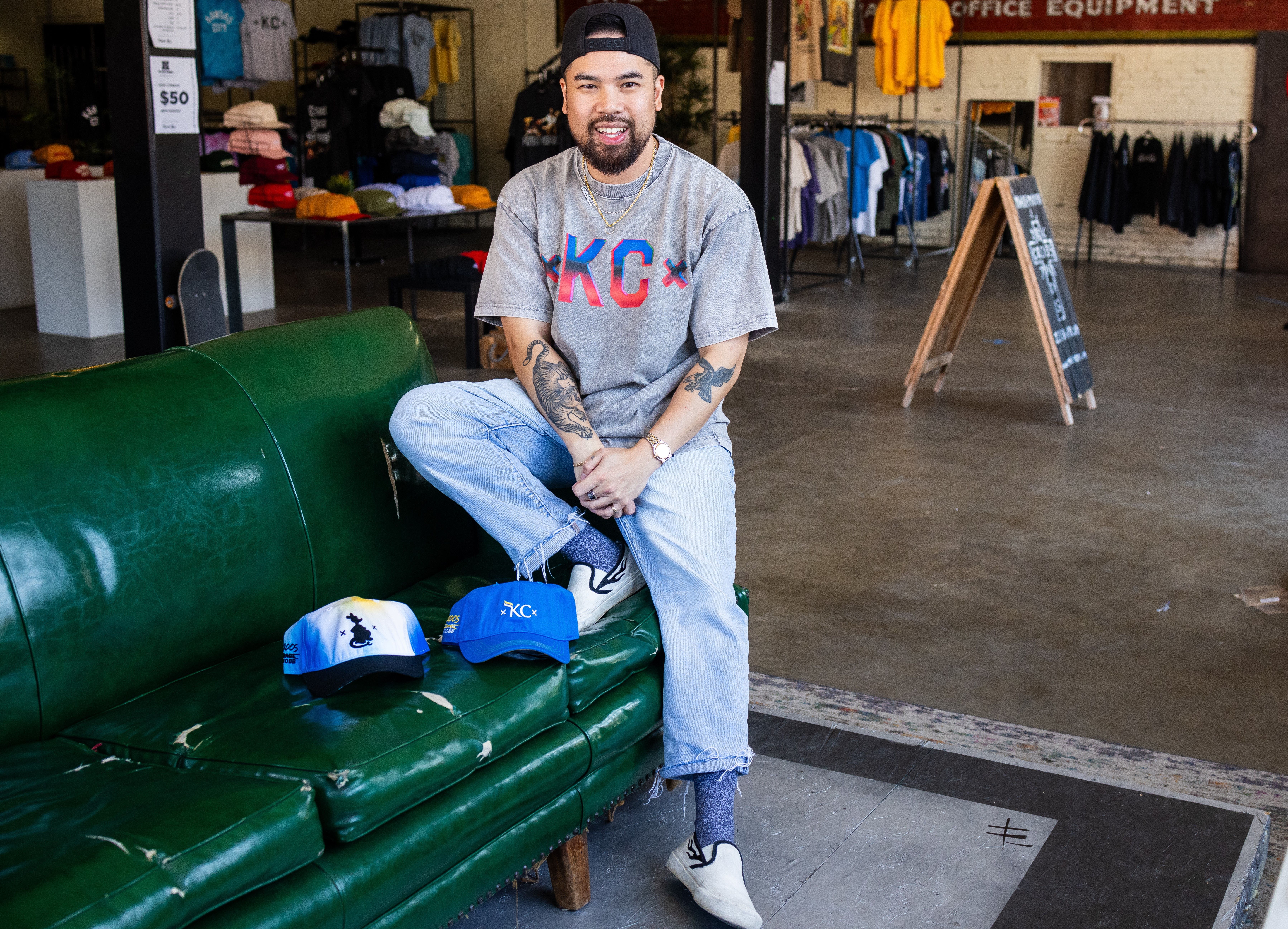 Vu Radley sitting on a couch posed with two Made Mobb and UMKC hats.