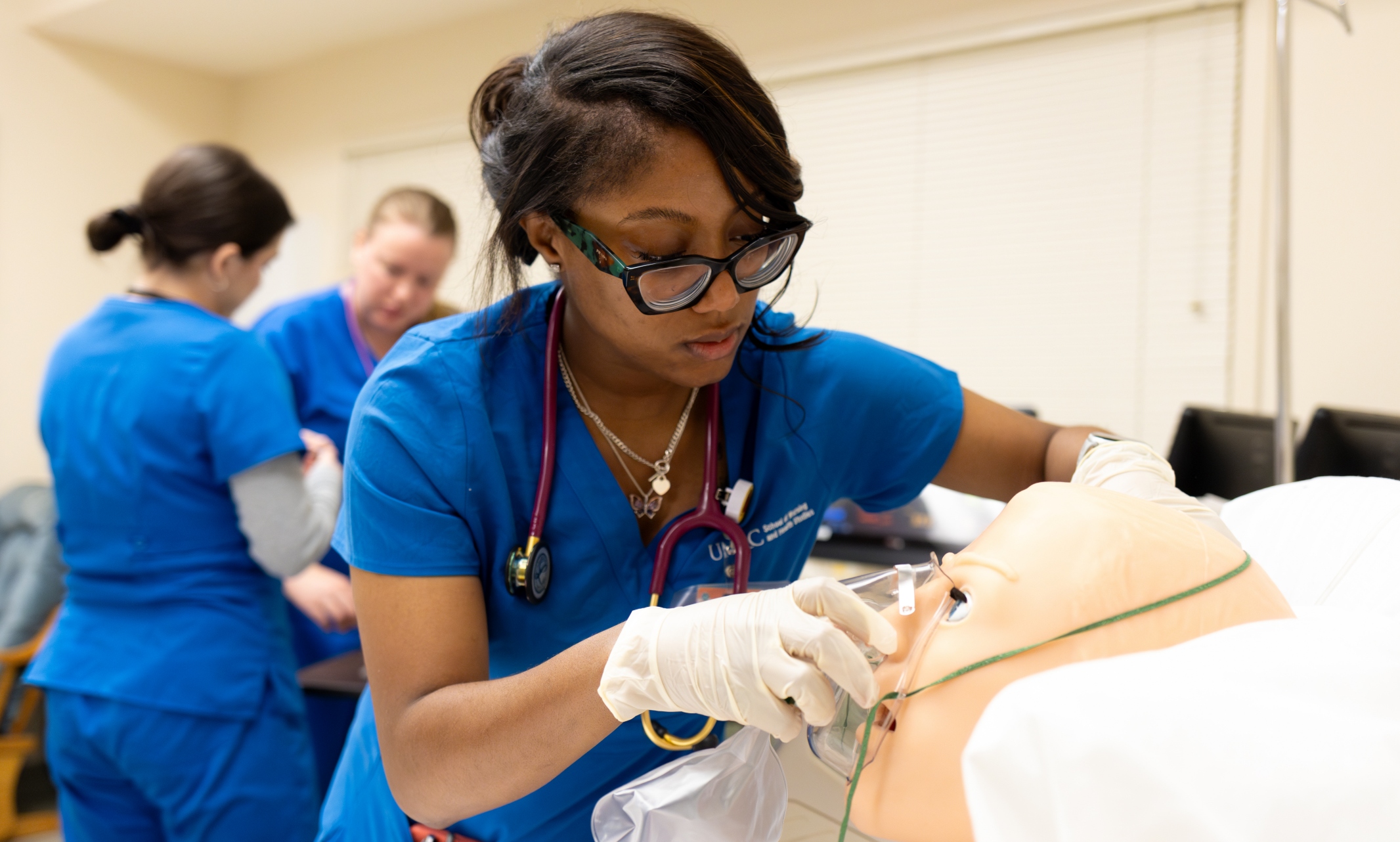 A nursing student fits an oxygen mask over a mannequin 
